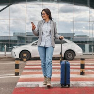 Happy caucasian woman traveller in airport terminal with luggage